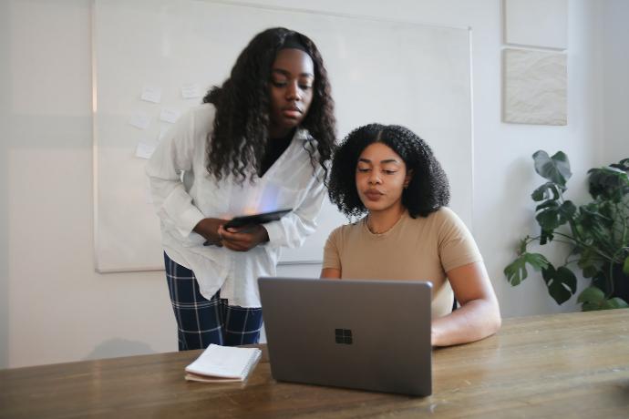 Female colleagues collaborating with a Surface laptop in a board room 